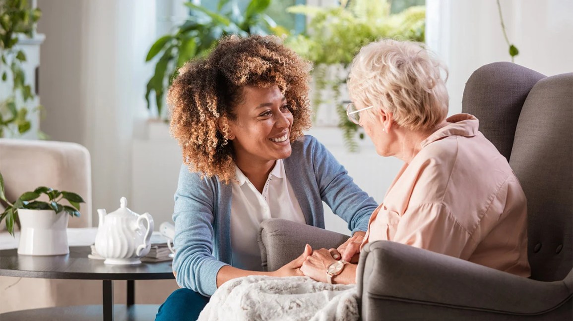 Home health aide comforting an older woman.
