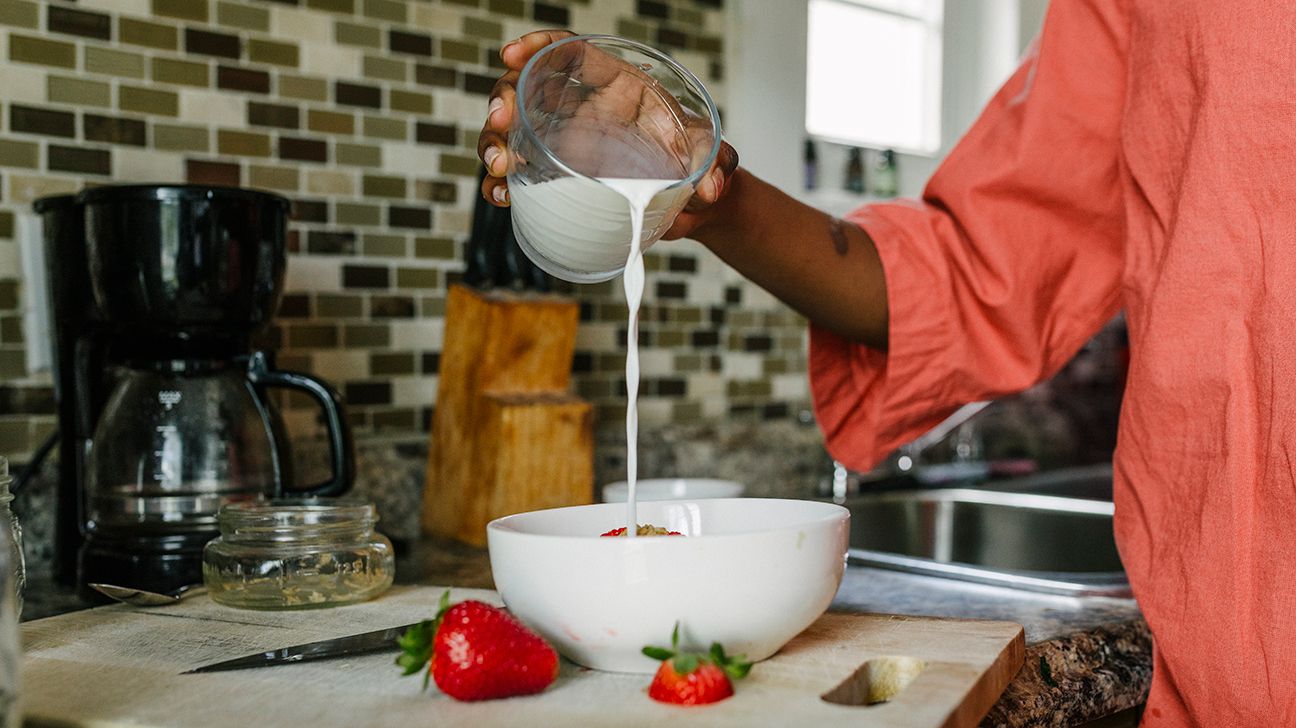 person pouring milk into cereal bowl