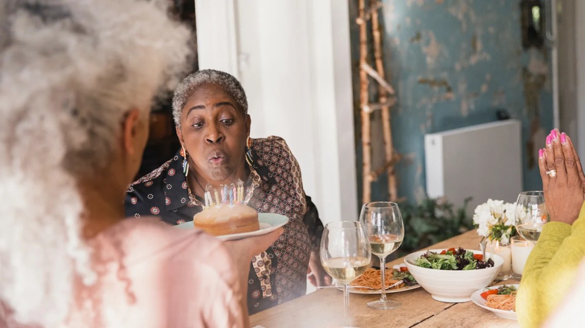 woman blowing out candles on a birthday cake